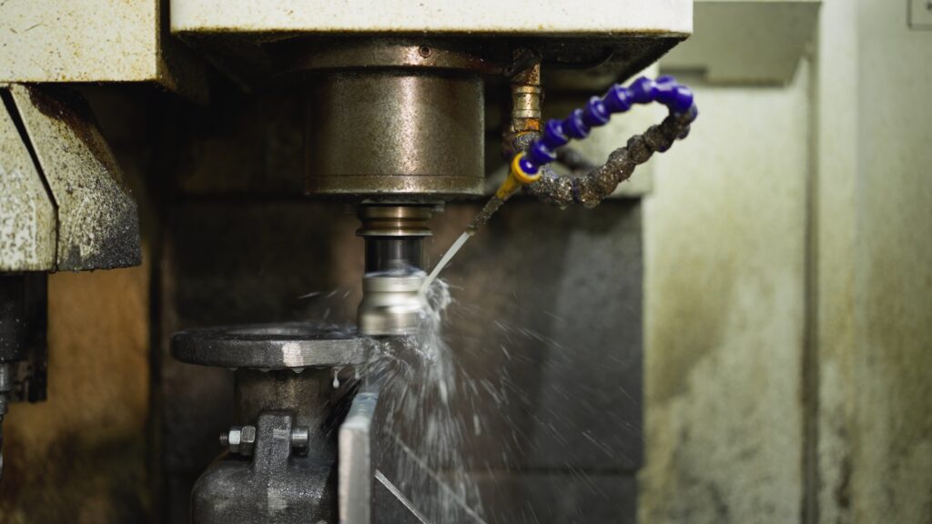 close up of cnc machine at work with coolant spraying on rotating metal part SBI 349471687